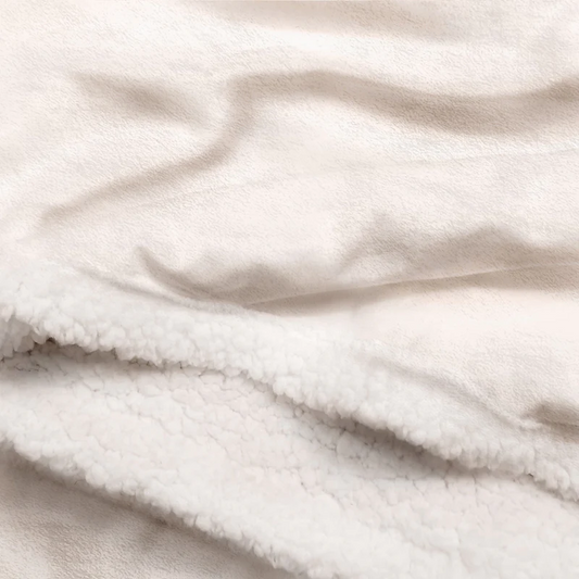 Close-up of a soft, cream-colored custom fleece blanket texture, highlighting the sherpa fleece material.